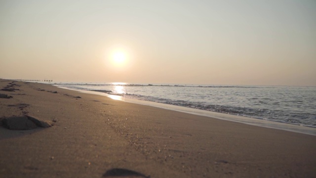 镜头沿着平静的沙滩移动。夕阳西下，地中海的海浪翻滚到沙滩上。美丽的土耳其日出。完美的平静的水。视频素材