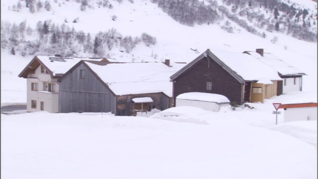 在滑雪小屋上方的斜坡上，一座石头建筑大部分被雪覆盖。视频素材