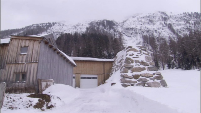 建筑矗立在白雪覆盖的田野边缘。视频素材