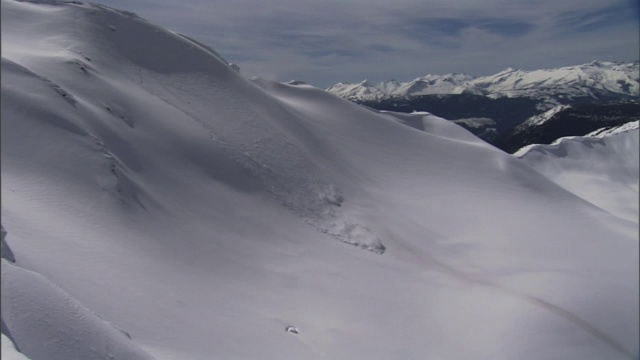 爆炸会在陡峭的山坡上引发雪崩。视频素材