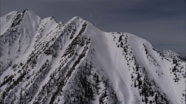 一场雪崩开始从一个崎岖的山顶流下来。视频素材