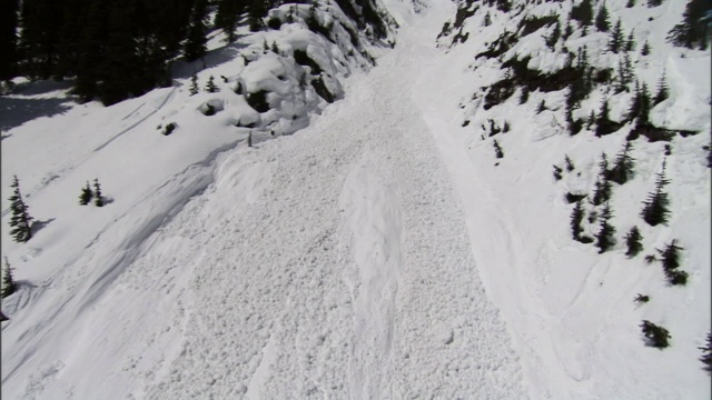 雪崩顺着陡峭的山腰峡谷而下。视频素材