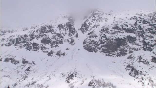 白雪覆盖了一座高山和山脚下的小社区。视频素材