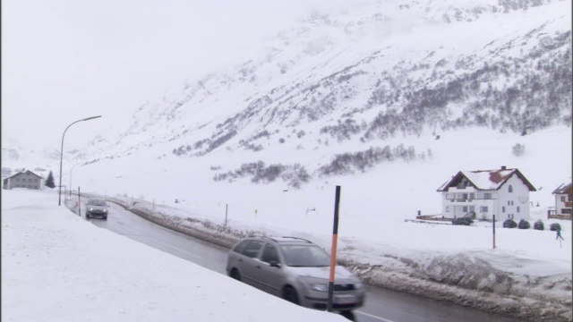 两辆车行驶在一条被积雪覆盖的道路上。视频素材