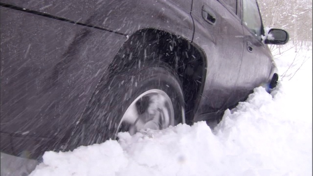 一辆汽车在雪地里转动轮子。视频素材