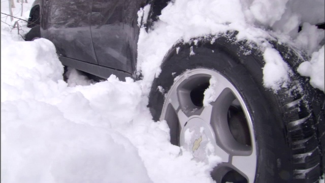 一辆汽车在雪地里转动轮子。视频素材