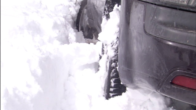 一辆汽车在雪地里转动轮子。视频素材