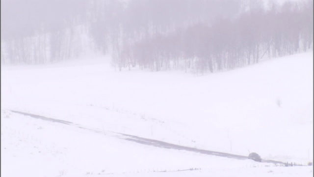 一辆汽车在下雪的路上行驶。视频素材