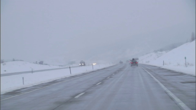 一辆汽车在下雪潮湿的公路上行驶。视频素材