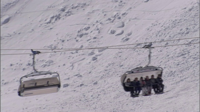 滑雪缆车载着滑雪者在雪坡上上下滑行。视频素材