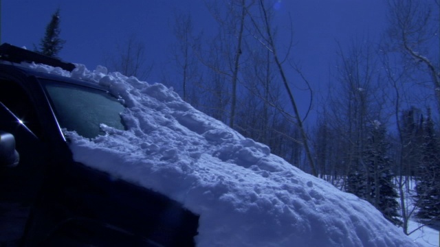 一场暴风雪过后，一辆被困在森林里的汽车被大雪覆盖。视频素材