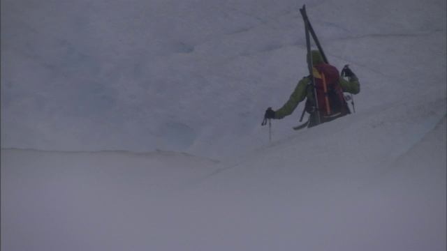 两个滑雪者艰难地穿越冰川。视频素材