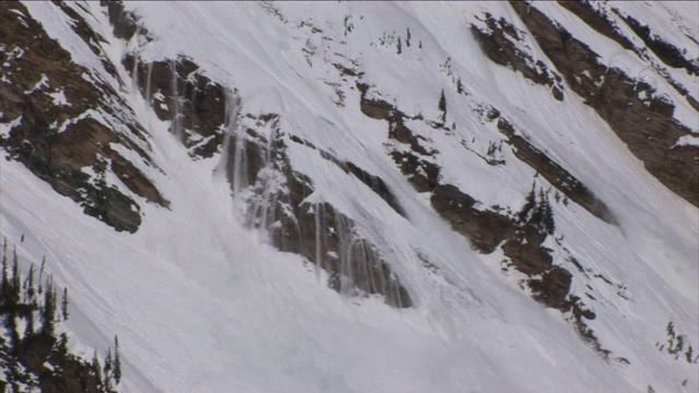 雪从崎岖的山坡上滚落下来。视频素材