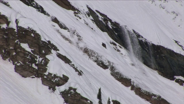 雪从崎岖的山坡上滑下来。视频素材