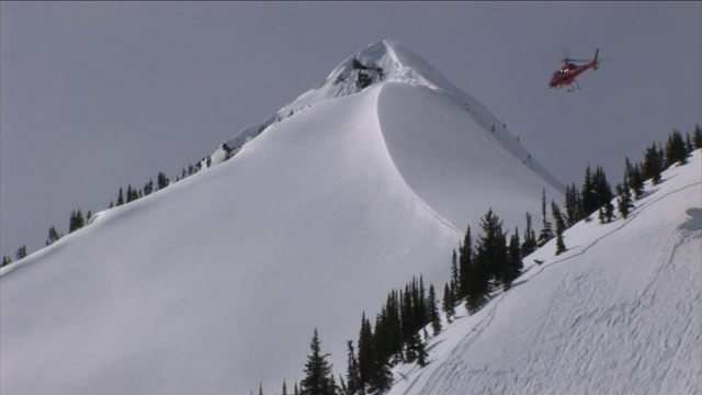 一架直升机在白雪覆盖的山峰上空盘旋。视频素材