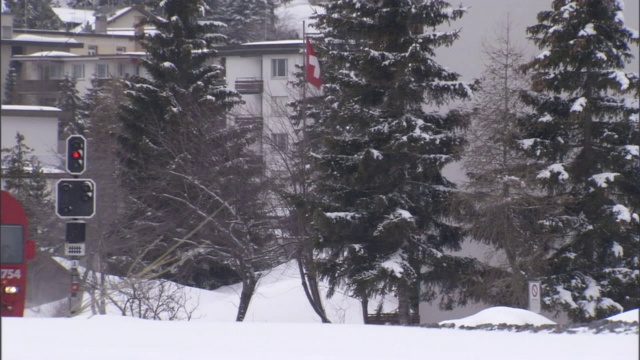 一列通勤列车载着乘客穿过白雪覆盖的瑞士小镇。视频素材