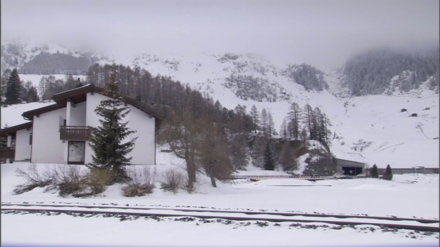 在积雪覆盖的农村地区，铁轨穿过住宅和商业建筑。视频素材