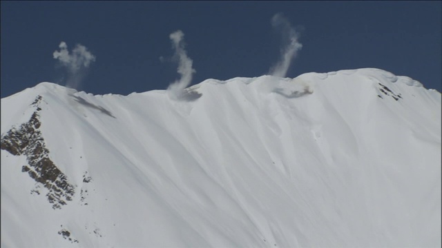 爆炸会在陡峭的山坡上引发雪崩。视频素材