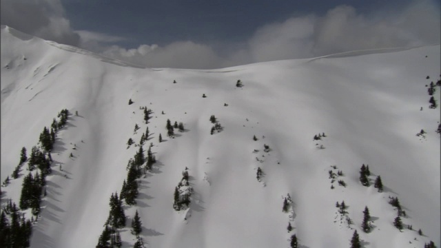 厚厚的云层和蓝天覆盖着白雪覆盖的山峰。视频素材