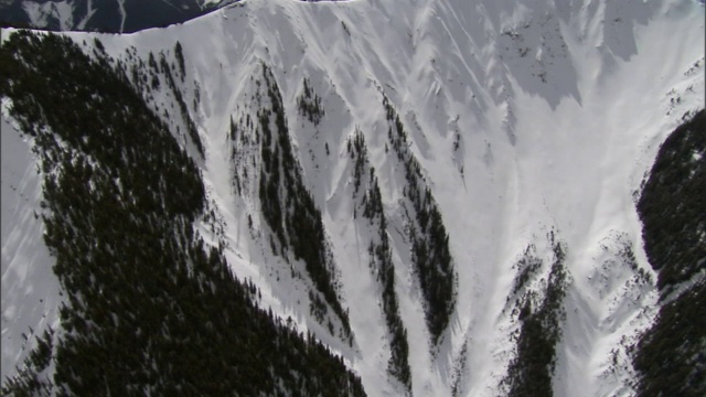 厚厚的白云与皑皑白雪覆盖的陡峭山坡融为一体。视频素材