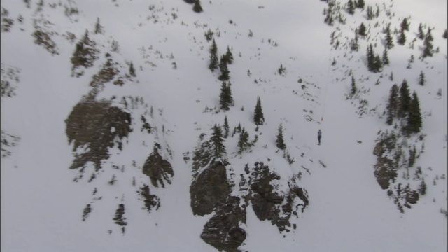 一架直升机将人体模型运送到白雪覆盖的山坡上。视频素材