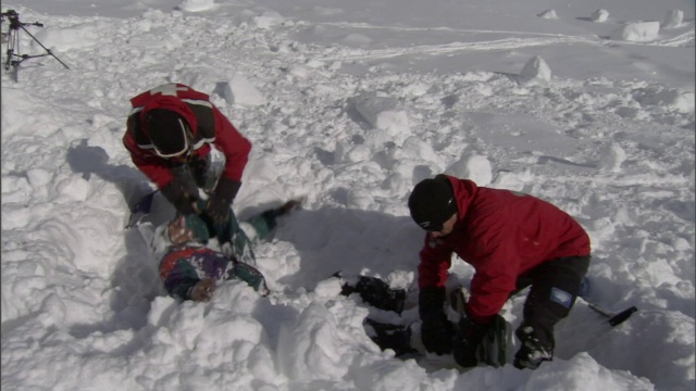 雪崩后，两名救援人员正在挖掘一名被埋在雪中的受害者。视频素材