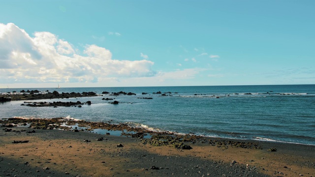 碧绿的海水。岛上的海滩上有黑色的火山沙。白云悬在海面上。自由，和平的概念视频素材