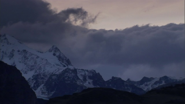 厚厚的云层盘旋在雪山的山峰上。视频素材