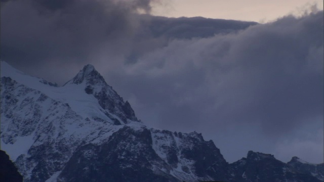 浓密的云在雪山之间沉淀。视频素材