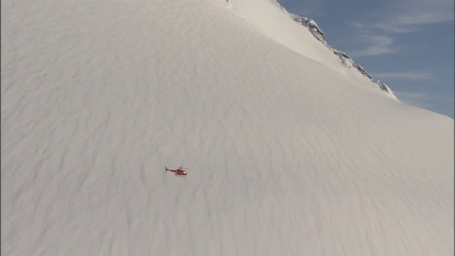 一架直升机在雪山边飞行。视频素材