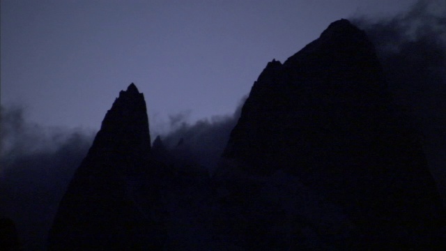 夜间浓雾盘旋并聚集在两座山峰周围。视频素材