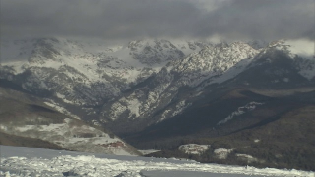 乌云在白雪皑皑的山峰上盘旋。视频素材