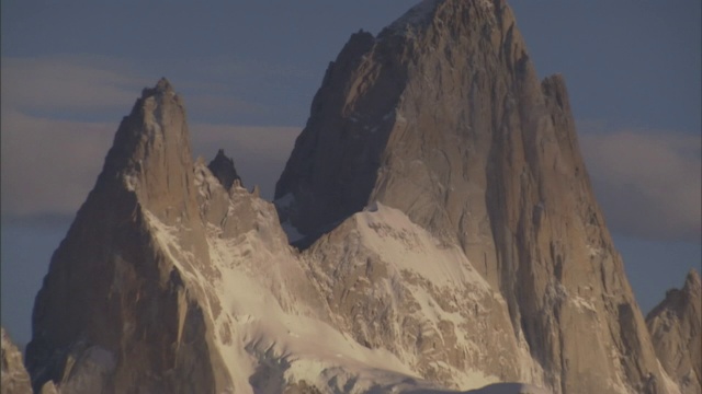 白雪覆盖的山峰与多云的蓝天相映成趣。视频素材