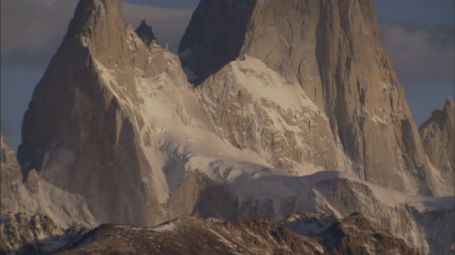 白雪覆盖的山峰与多云的蓝天相映成趣。视频素材