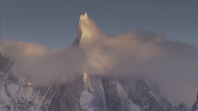 一座白雪皑皑的山峰耸立在白云之上。视频素材