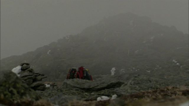 一场暴风雪将雪吹过三个在山里徒步旅行的成年人。视频素材