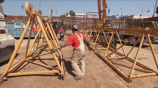 在建筑工人的帮助下，起重机吊起并转动钢结构。视频素材