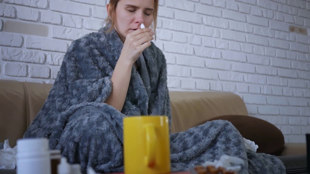 一位年轻女子用鼻喷剂来治疗感冒。感冒流感的概念。视频素材