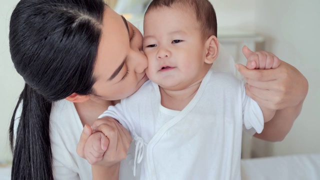 妈妈和她的孩子在卧室里玩。快乐幸福的家庭。家庭关系，亚洲家庭，新生儿，人寿保险。关系与人、儿童、童年与亲子观念。东南亚和东亚:亚洲婴儿视频素材