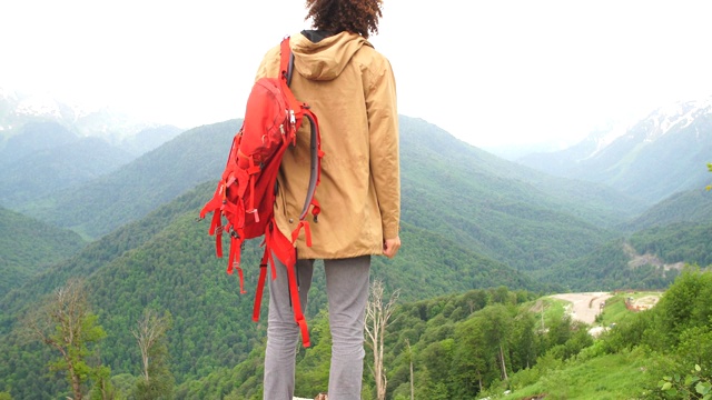 一个背着背包的男人举起了手。背景为山脉景观视频素材