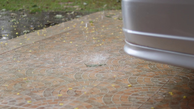 雨水落在汽车的后保险杠上。潮湿的地面上的叶子强烈的雨天。视频下载