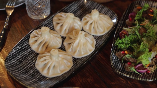 传统的格鲁吉亚饺子，Khinkali，桌上有沙拉。准备吃格鲁吉亚菜了视频素材