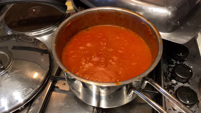 在厨房的钢制炖锅里煮红酱，制作肉酱面番茄酱。视频素材