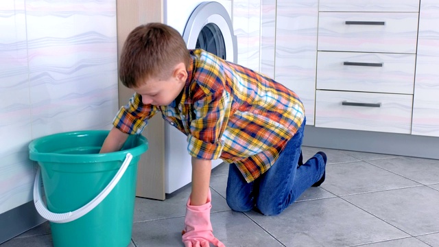 男孩戴上橡胶手套打扫厨房地板。孩子的家庭职责。视频素材