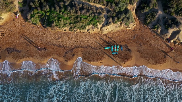 Ghajn Tuffieha海滩鸟瞰图。冲浪者。日落，青山绿水，沙滩，海浪在海里。冬天。摄像机从下往上移动。马耳他视频素材