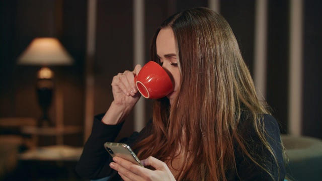 商业女性在家里使用智能手机。商人喝茶视频素材