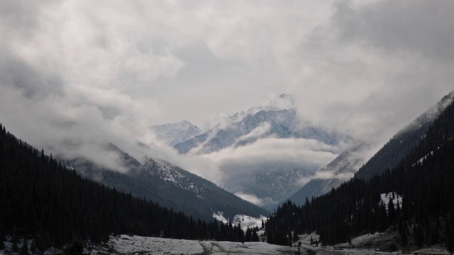 广阔的雪景覆盖草地与戏剧性的天空和雪山在远处。视频素材