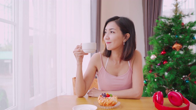 年轻的女人穿着性感的衣服在她房子的客厅里喝咖啡。视频素材