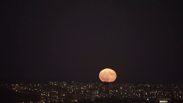 升起的超级满月在夜晚的城市。视频素材