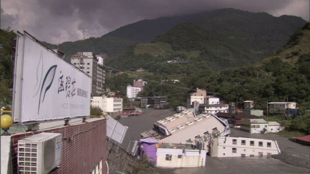 郁郁葱葱的山峰和被飓风淹没的小镇上空，乌云密布。视频素材